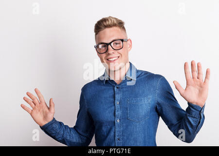 Portrait of a happy young man in a studio, wearing blue denim shirt. Stock Photo