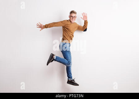 Portrait of a happy young man in a studio, jumping. Stock Photo