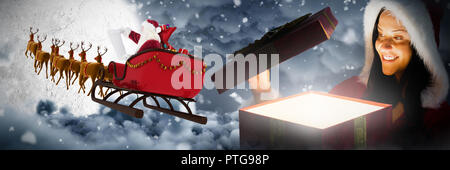 Composite image of smiling woman opening christmas present Stock Photo