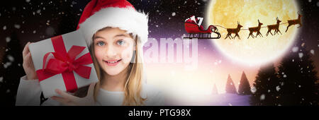 Composite image of portrait of smiling girl holding christmas gift against white background Stock Photo