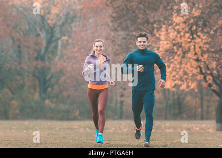 Couple in wonderful fall landscape running for better fitness towards the camera Stock Photo