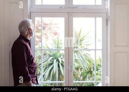 Thoughtful senior man looking out window Stock Photo