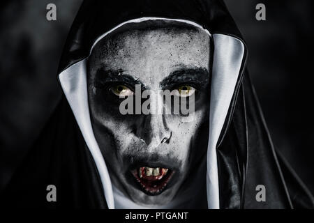 closeup of a frightening evil nun, with bloody teeth and scary eyes, wearing a typical black and white habit Stock Photo