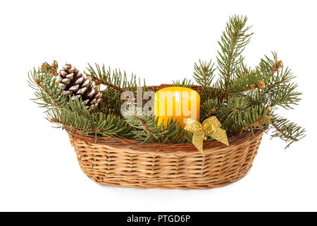 Burning candle, cone and natural fir tree branches in wicker basket isolated on white background. Christmas and New Year concept Stock Photo