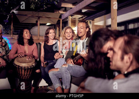 Friends hanging out, playing music on patio at night Stock Photo