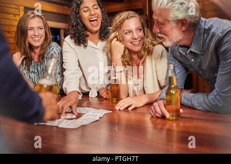 Friends playing card game at cabin table Stock Photo