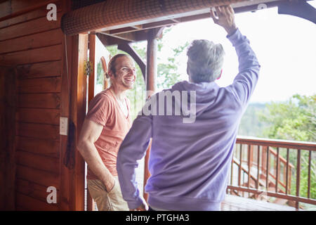 Father and son talking at cabin patio doorway Stock Photo