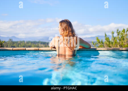 Serene woman in sunny swimming pool Stock Photo