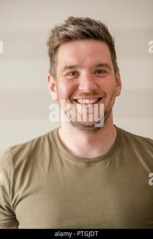 Mid-adult man in a green t-shirt smiling while looking at the camera for a portrait. Stock Photo