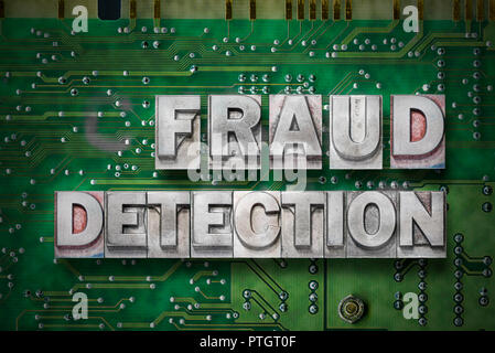 fraud detection phrase made from metallic letterpress blocks on the pc board background Stock Photo
