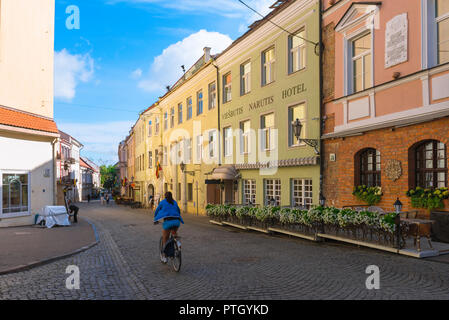 Vilnius old town, view on a summer morning of a young woman cycling along Pilies Gatve - the main thoroughfare in Vilnius Old Town, Lithuania. Stock Photo