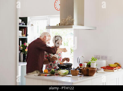 Active senior couple cooking in kitchen Stock Photo