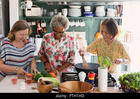 Active senior women friends cooking in kitchen Stock Photo