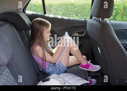 Girl doing homework in back seat of car Stock Photo