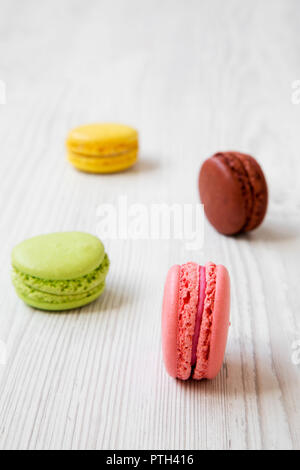 Sweet and colorful macaroons on a white wooden background, side view. Selective focus. Stock Photo