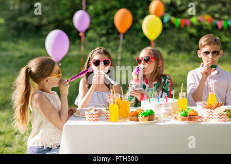 happy kids blowing party horns at summer birthday Stock Photo