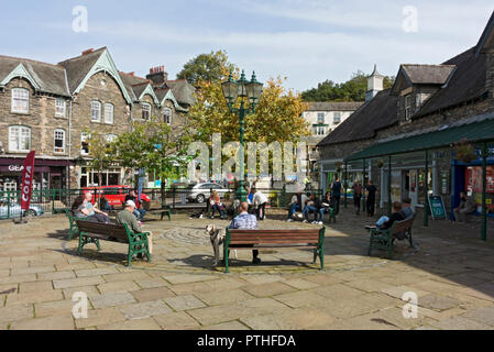 People tourists visitors relaxing sitting outside in the town centre in summer Ambleside Cumbria England UK United Kingdom GB Great Britain Stock Photo