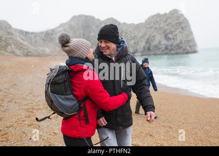 Affectionate, happy couple in warm clothing on snowy winter beach Stock Photo