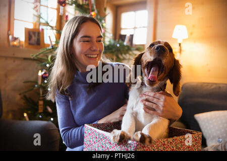 Happy teenage girl with yawning dog in Christmas gift box Stock Photo