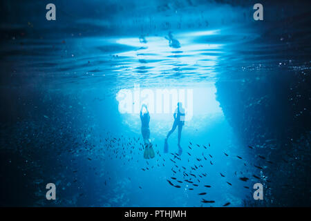 Couple snorkeling underwater among fish, Vava'u, Tonga, Pacific Ocean Stock Photo