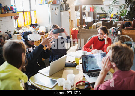 Young college student friends studying, using virtual reality simulator glasses at kitchen table in apartment Stock Photo