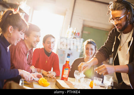 Young adult friends making cocktails at kitchen table Stock Photo