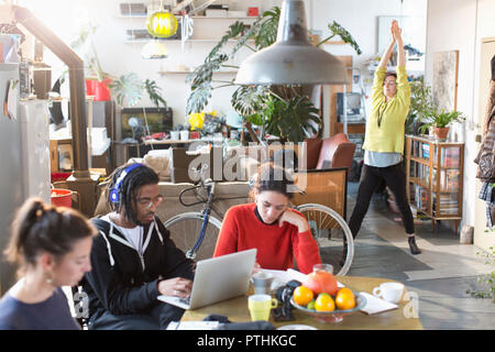 Young college student roommates studying and stretching in apartment Stock Photo