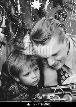Christmas in the 1940s. A father and son are playing with a toy steam engine by the christmas tree. Sweden 1940s Stock Photo
