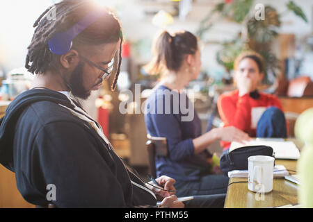 Young man with headphones studying at kitchen table Stock Photo