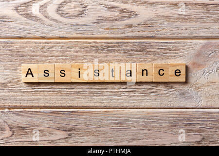 ASSISTANCE word written on wood block. ASSISTANCE text on table, concept. Stock Photo
