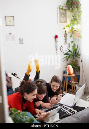 Young female college students studying, using digital tablet and laptop on bed Stock Photo