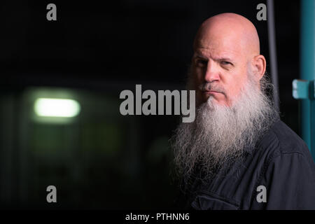 Portrait Of Bald Man With Gray Beard Outdoors At Night Stock Photo
