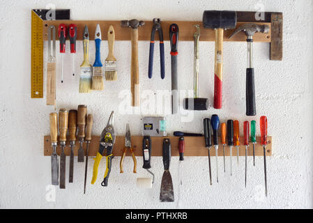 Woodworking Tools & Hand Tools including Screw Drivers, Paint Brushes and Hammers Hanging in Workshop or Garage Wall-Mounted Tool Rack Stock Photo