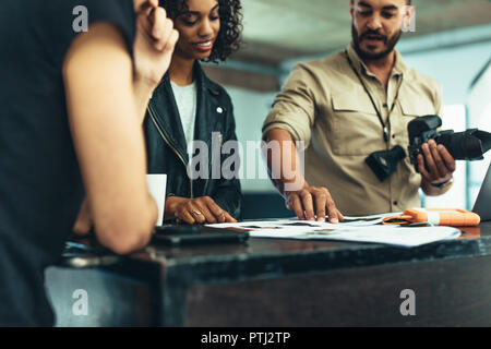Photographer holding camera discussing photo shoot with his team. Photographer sharing ideas on the photo shoot with a model. Stock Photo