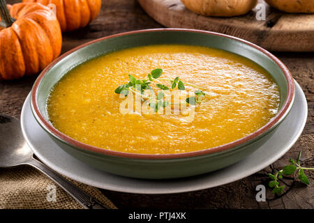 A bowl of delicious homemade pumpkin squash soup with fresh thyme garnish. Stock Photo