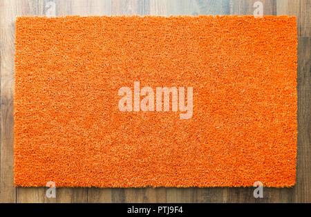 Blank Orange Welcome Mat On Wood Floor Background Ready For Your Own Text. Stock Photo