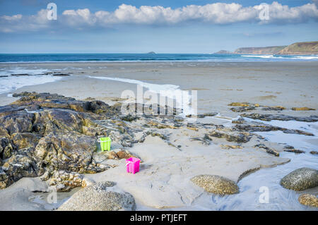 Two brightly coloured plastic buckets left on the beach at Sennen Cove in Cornwall. Stock Photo