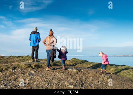 A family standing on Towan Head and enjoying the view over Newquay Bay in Cornwall. Stock Photo