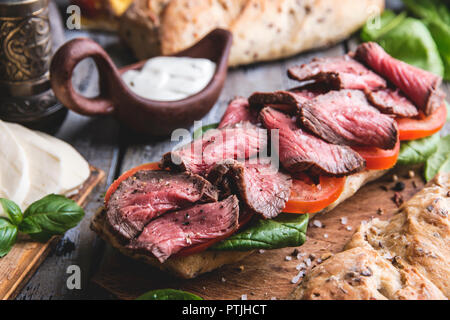 Steak sandwich, sliced roast beef. bread, mozzarella cheese,spinach leaves,tomato Stock Photo