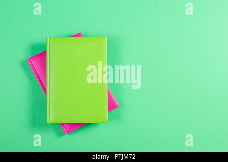 Green and pink hardcover books on green background. Stock Photo