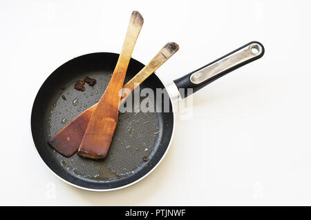 Dirty frying pan with cooking utensils on a white background. Stock Photo