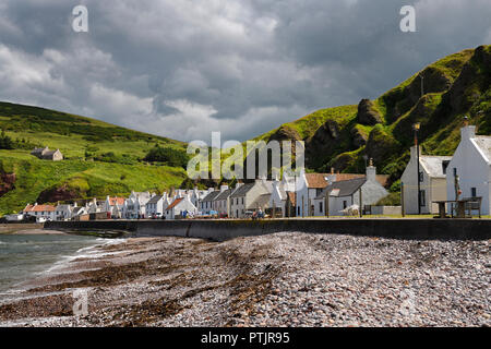 Stone beach and row of white houses of Pennan coastal fishing village on North Sea in Aberdeenshire Scotland UK with green sea cliffs Stock Photo