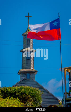 CHILOE, CHILE - SEPTEMBER, 27, 2018: Outdoor view of wooden church of Vilupulli is a catholic temple in the locality of Vilupulli, in Chonchi south of Chile with a Chilean flag waving Stock Photo