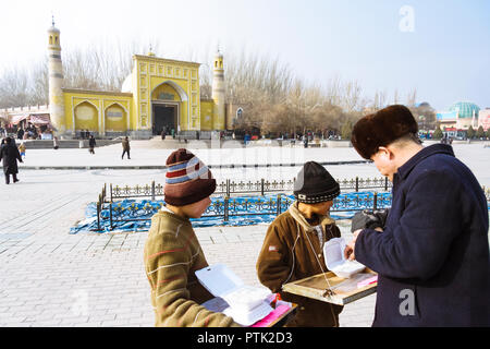 Kashgar, Xinjiang, China : Two Uyghur children sell sweets opposite the yellow-tiled Id Kah Mosque (1442), the spiritual and physical heart of the cit Stock Photo