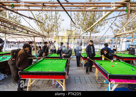Kashgar, Xinjiang, China : Uyghur men play pool opposite the yellow-tiled Id Kah Mosque (1442) the spiritual and physical heart of the city and the la Stock Photo