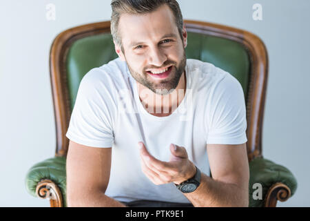 cheerful man sitting in green armchair, isolated on white Stock Photo