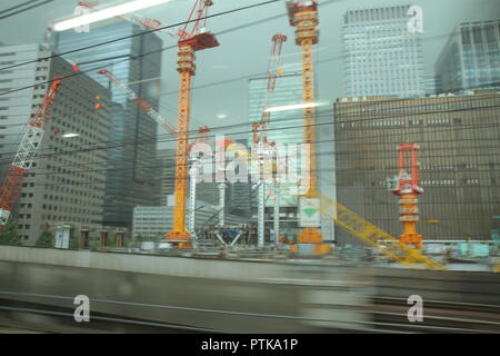 Tokyo buildings in construction : A view of the business district from the window of a fast passing train, on a grey, rainy afternoon. Stock Photo