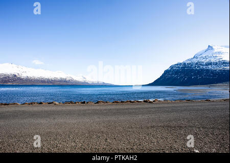 Seydisfjordur, Eastern Fjords, Iceland. Snow capped mountain peaks, sparkling waters and blue sky background Stock Photo