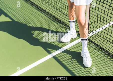 partial view of female tennis player standing near tennis net on court Stock Photo