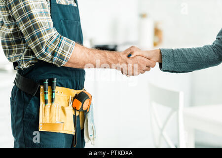 cropped image of plumber and client shaking hands in kitchen Stock Photo